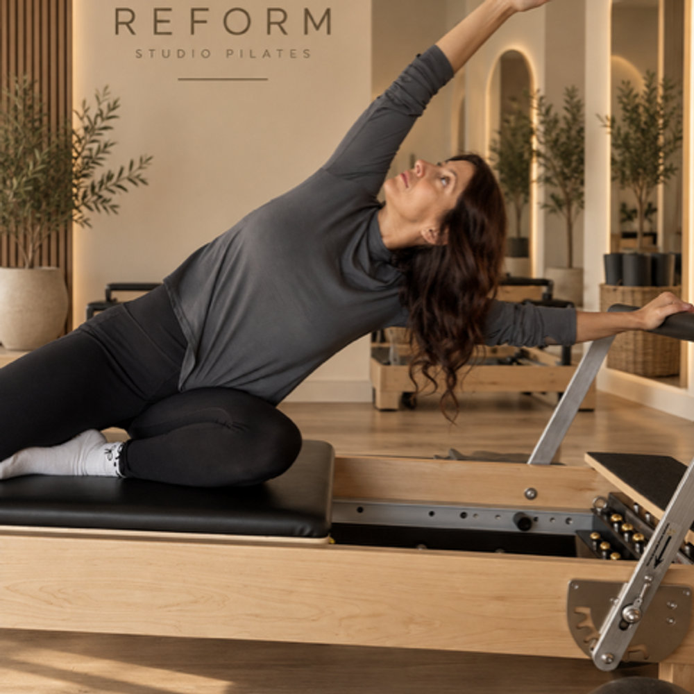 Cliente en étirement latéral sur un appareil Pilates Reformer au studio de Saint-Lin